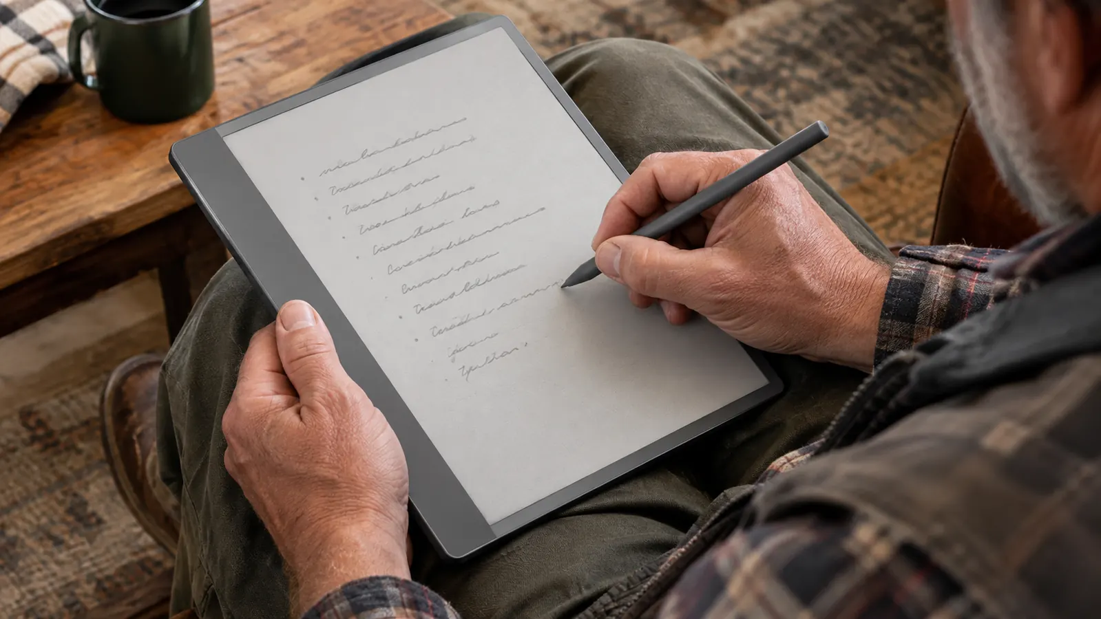 A hand writing on the large e-ink screen with a stylus, the device resting on a lap